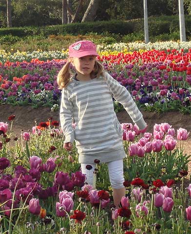 C&ocirc; b&eacute; đang vui đ&ugrave;a giữa vườn hoa tựa như thi&ecirc;n thần dưới &aacute;ng nắng của m&ugrave;a xu&acirc;n