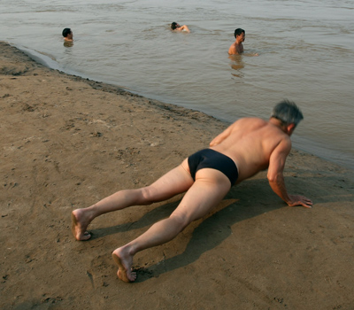 Một người đang chống đẩy để luyện cơ ngực, bụng và tay trên cát.