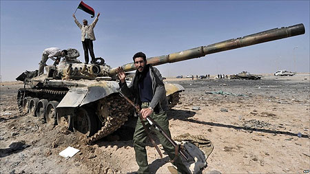Lực lượng chống đối Libya ăn mừng bên chiếc xe tăng bị liên quân tiêu diệt. Ảnh: AFP