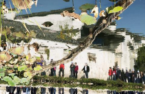 Bóng du khách tới thăm làng cổ soi bóng xuống hồ nước trong xanh.