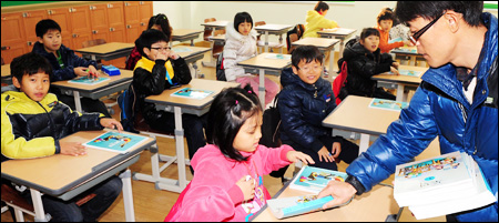 Học sinh lớp 3 một trường tiểu học ở Hàn Quốc được thầy giáo phát sách giáo khoa mới. Chính phủ Hàn Quốc đang lên kế hoạch số hóa sách giáo khoa đến trước năm 2015. (Ảnh: Korea Times)
