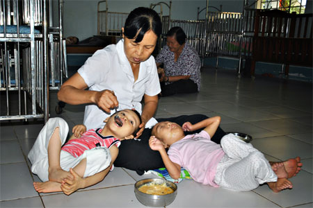 Chị Trần Thị Ngọc Xinh bón thức ăn cho các em bị bại não.
