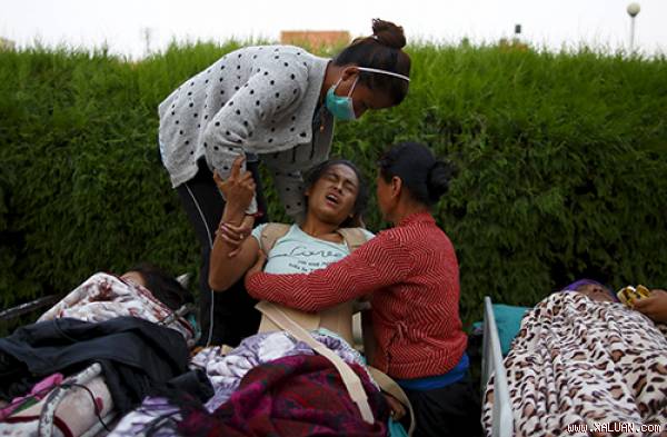 Một nạn nhân động đất đau đớn khi bị chuyển từ bệnh viện ra một khu trại ngoài trời để chữa trị vào hôm qua. Ảnh: Reuters