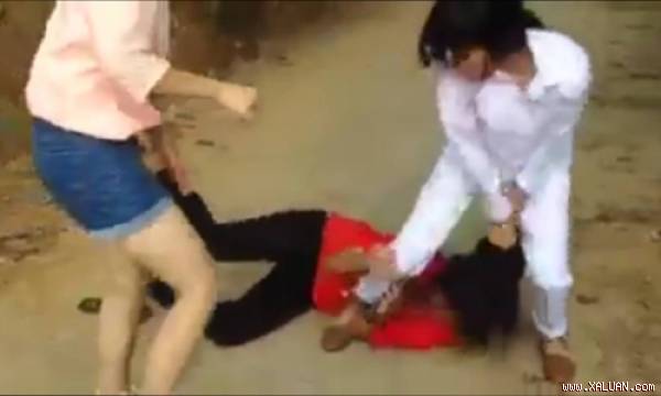  Hai nữ sinh áo hồng, áo trắng cùng lao vào túm tóc, đánh đập nữ sinh áo đỏ. Ảnh cắt từ clip.
