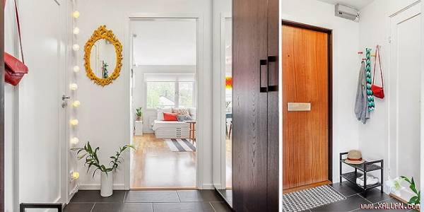 Sự kết hợp giữa gam trầm của cửa chính với bức tường màu trắng xung quanh giúp lối nhỏ vào nhà được hài hòa hơn về sắc độ.