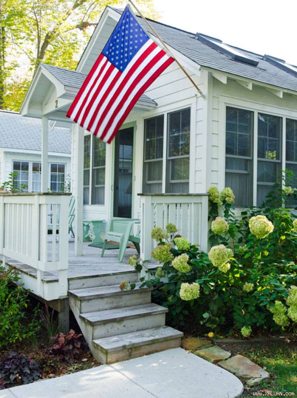 Ngôi nhà nhỏ nép mình dưới tán lá xanh rì, bao quanh là những khóm hoa xinh.