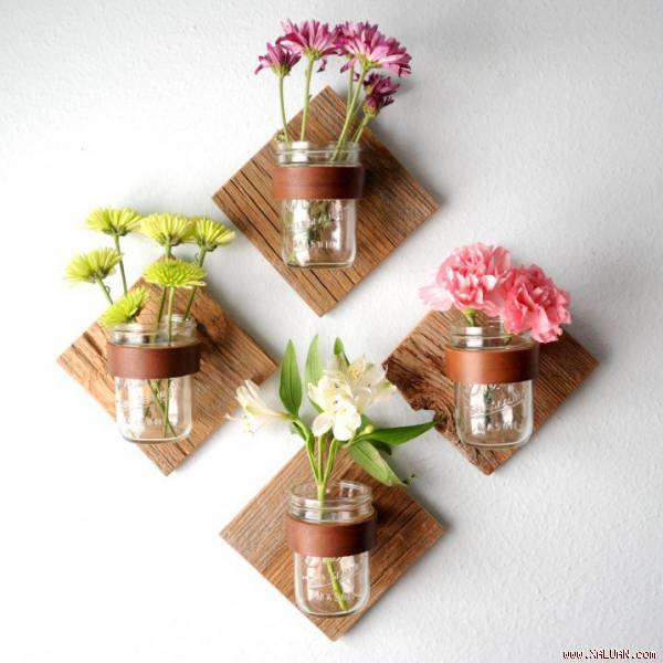  Những bông hoa tươi, mỗi loại vài bông được bỏ vào lọ thủy tinh trong suốt đính trên bảng gỗ cố định ở tường tạo thành hình vuông.