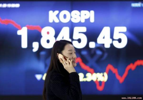 Một phụ nữ nói chuyện điện thoại trước tấm biển điện tử chạy chỉ số chứng khoán KOSPI ở Sở chứng khoán Hàn Quốc tại thủ đô Seoul ngày 21/1/2016. Ảnh: Reuters