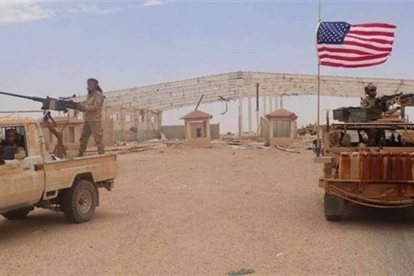 Một phiến quân trên chiếc xe được trang bị súng máy hạng nặng (bên trái) gần một binh sĩ Mỹ trên xe bọc thép tại trạm kiểm soát biên giới Syria-Iraq ở Tanf. Bức ảnh chụp vào ngày 23.5.2017.