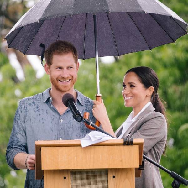 Công nương Meghan âu yếm che ô cho Hoàng tử Harry dưới mưa nặng hạt