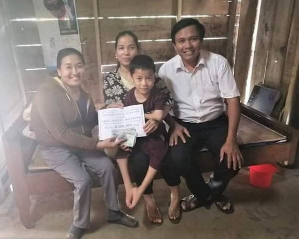 Tú trao tiền do cô quyên góp hỗ trợ học sinh Nguyễn Thế Phong (lớp 1A, Trường tiểu học số 1 Xuân Trạch) bị khuyết tật tứ chi