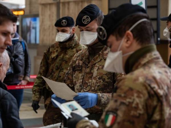 Một số binh sĩ Ý kiểm tra giấy tờ của hành khách đi ga tàu Attilio Fontana ở TP Milan hôm 10-3. 